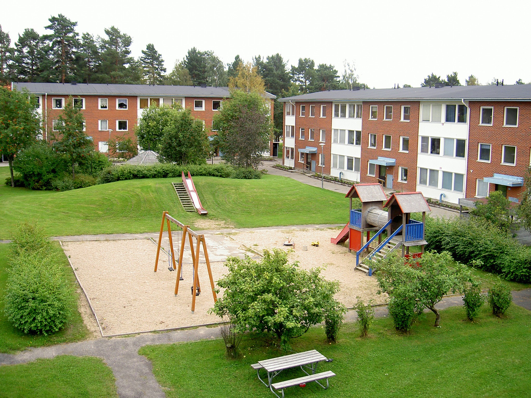 Lekplats med två hyreshus i bakgrunden.